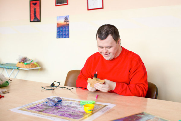 An adult man with Down syndrome glues paper in the workshop at Special Care Dentistry of Oregon in Albany, OR