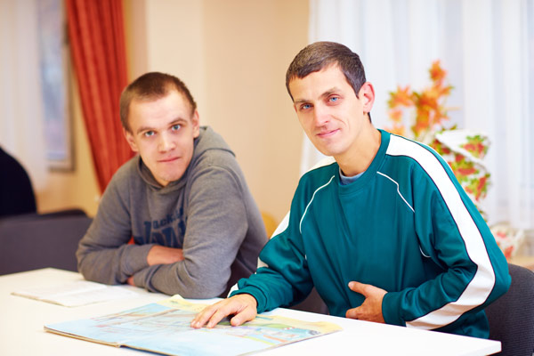 Cheerful adult men with special needs sitting at a desk in the rehabilitation center at Special Care Dentistry of Oregon in Albany, OR