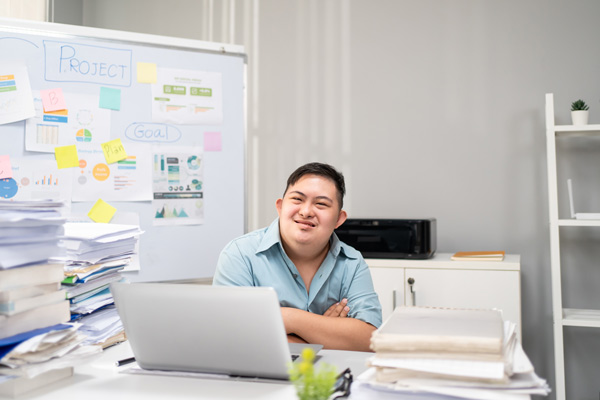 Young businessman with down syndrome smiling and working in office