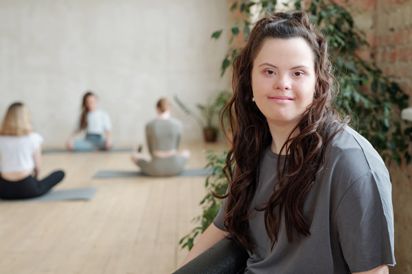 Brunette female with down syndrome smiling while at yoga class