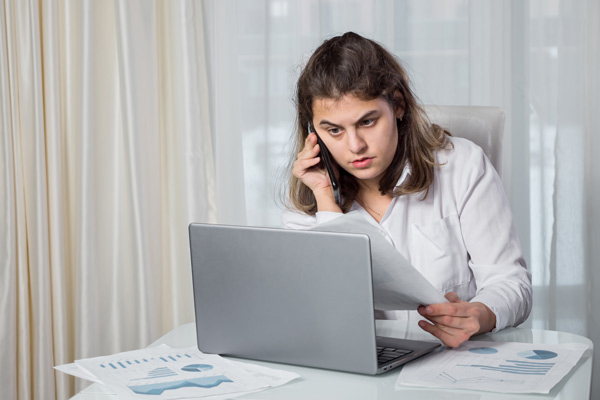 Disabled woman talking on phone while looking at laptop